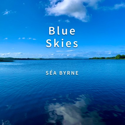 A shot looking across Lough Derg with sky and water. Mostly blue skies with some clouds reflected upon the surface of the lake. "Blue Skies" and "Séa Byrne" text overlaid above the photograph.
